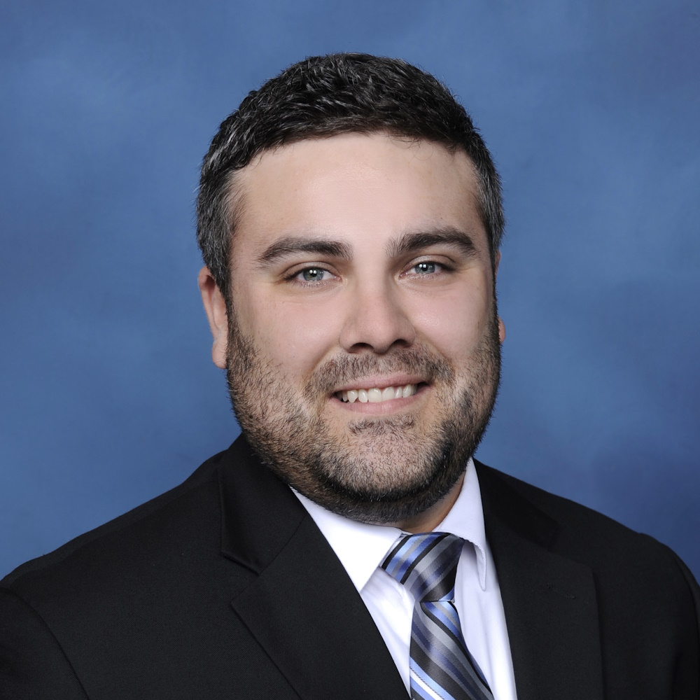 Headshot of Tom Bennets, a white man with black hair and a short salt and pepper beard.